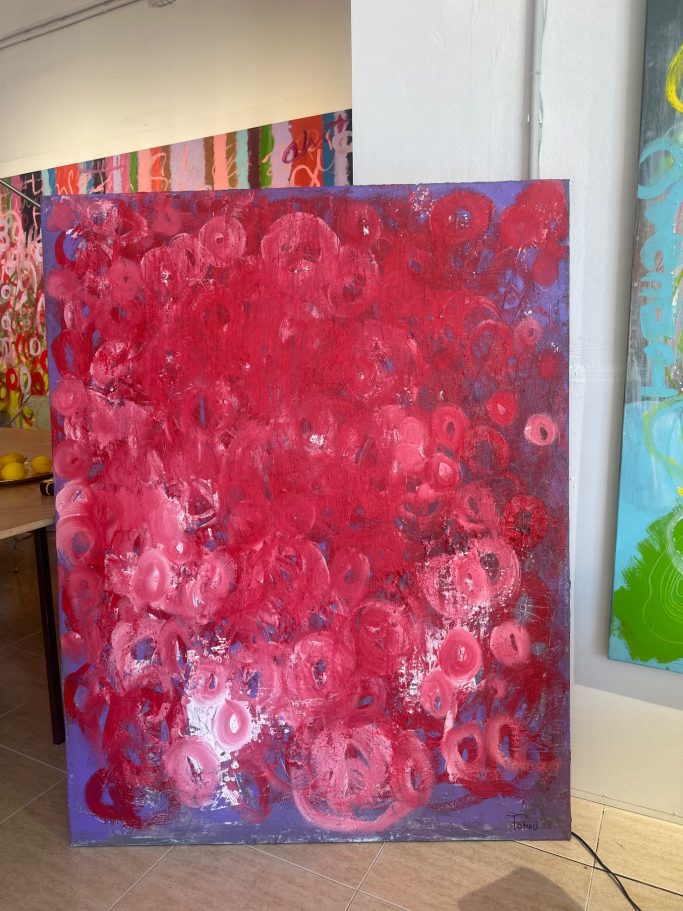 Pintura abstracta en tonos rojos con formas circulares y texturas variadas.