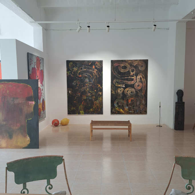 Sala de arte moderna con pinturas abstractas y una escultura negra. Muebles de diseño.