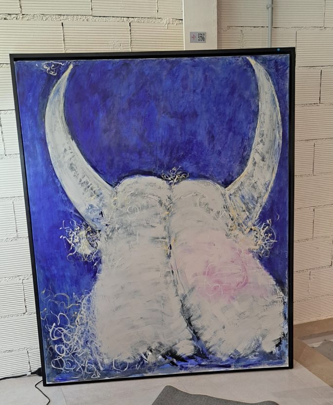 Dos cabezas de buey con cuernos grandes, fondo azul y detalles decorativos.
