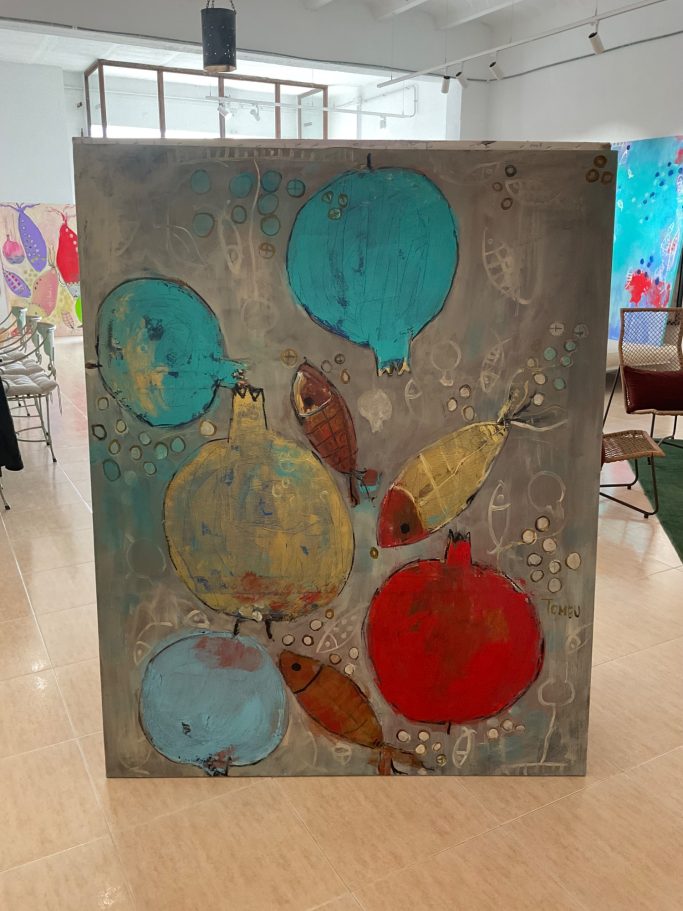 Pintura abstracta con granadas de colores azul, rojo y dorado sobre fondo gris.