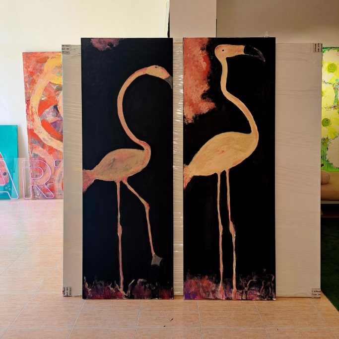 Dos flamencos estilizados en un fondo negro, uno con una pierna levantada.