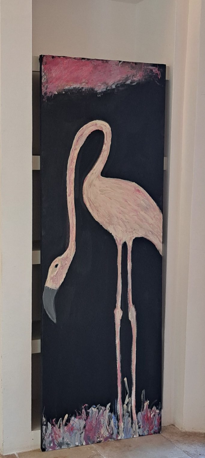 Puerta decorada con un flamenco rosa sobre un fondo oscuro.